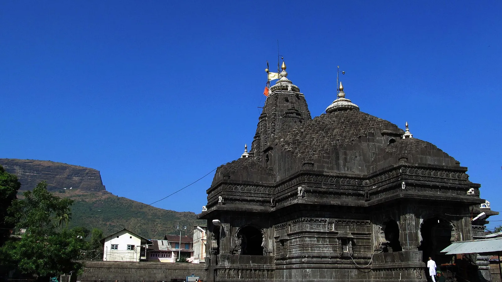 Trimbakeshwar Jyotirlinga temple against a clear sky, with Brahmagiri hill behind